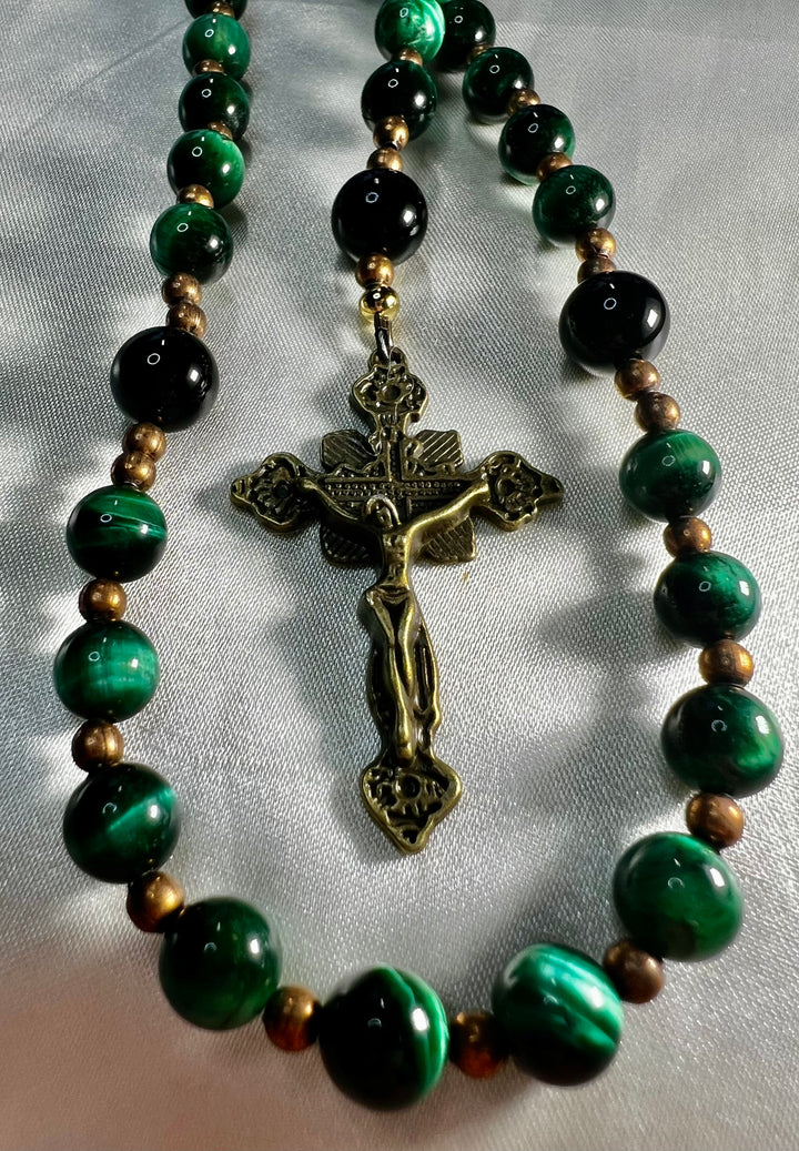Green and black beaded rosary with a crucifix pendant on a white background